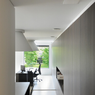 Foto van thuiskantoor met Vasco design ventielen in het plafond, een bureau met een bureaustoel en achteraan een raam waar je bomen ziet.