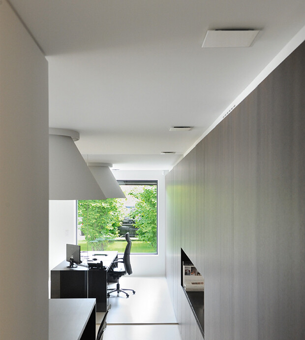 Foto van thuiskantoor met Vasco design ventielen in het plafond, een bureau met een bureaustoel en achteraan een raam waar je bomen ziet.